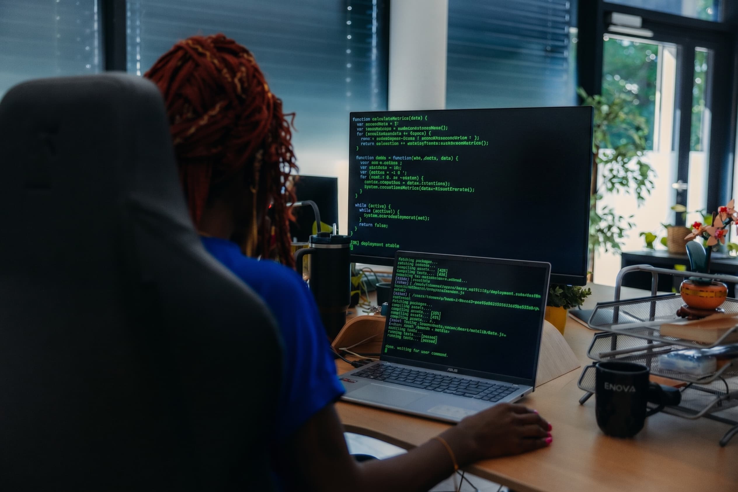 Person coding at a desk with two screens